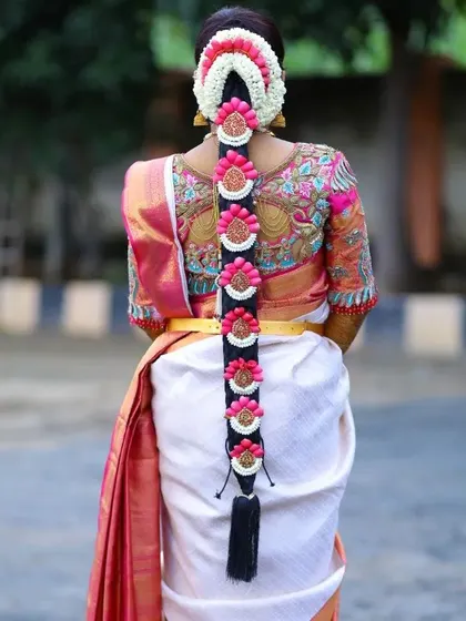The back of the blouse is just as important as the front. This view showcases a custom embroidered blouse with peacock motifs, perfectly complemented by the bride's traditional floral hair arrangement, creating a complete and stunning bridal look from every angle.