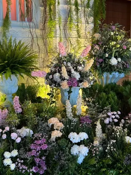 A lush bed of purple, pink, and white flowers in front of a stone-textured wall, showcasing the variety of florals used to create the garden landscape.