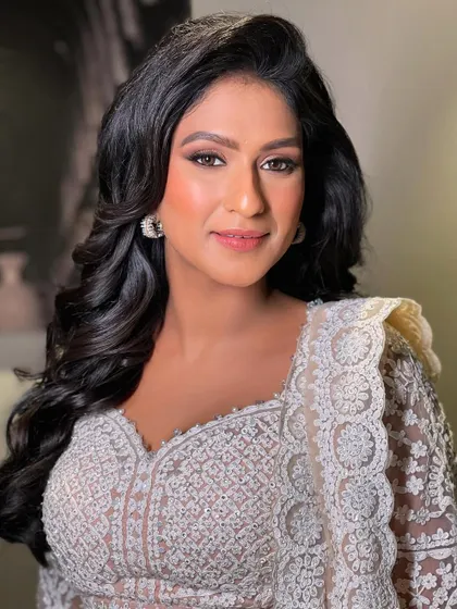 A perfect sangeet look with side-swept voluminous curls. This style is elegant and keeps the hair off one side of the face to highlight earrings.