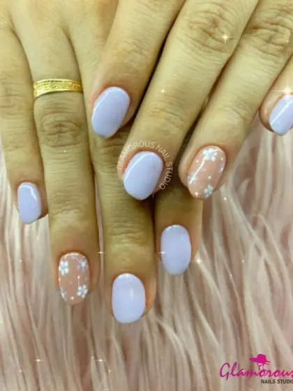 A delicate and pretty design featuring soft lavender nails paired with sheer accent nails adorned with tiny white daisies.