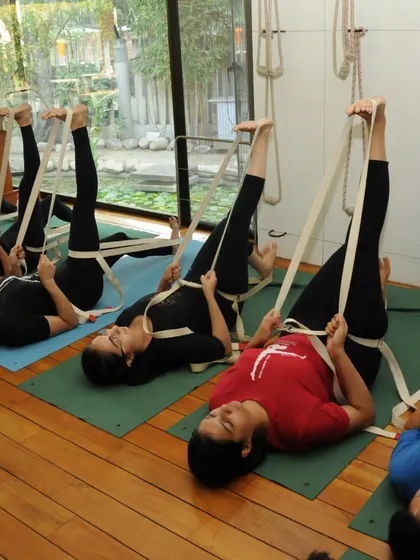 A class of students in a supine stretch. The quote from Guruji reminds us that while there is one reality, there are many ways to interpret it.