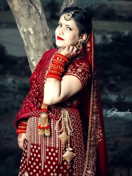 A beautiful three-quarter portrait of the bride, with the dark background making her red lehenga appear even more vibrant.