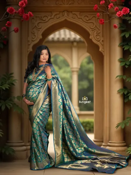The long trail of the teal silk saree creates a stunning visual against the garden archway. This is a beautiful pose for an outdoor or studio-based traditional maternity session.