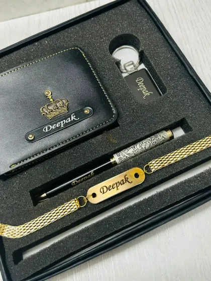 An elegant black and gold themed Rakhi gift set. It includes a wallet, pen, and bracelet, all personalized with the name 'Deepak' and a crown charm.
