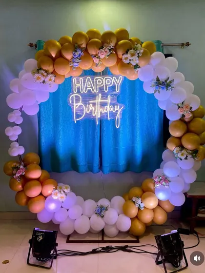 The lighting enhances the yellow and white balloon ring, making it a beautiful centerpiece for the celebration.
