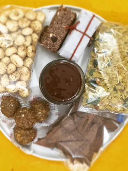 My Satvic Vegan travel essentials are perfect for staying healthy on the go. This platter includes spiced makhana, nutritional bars, millet flakes mixture, hazelnut nutella, and gluten-free baked nachos.