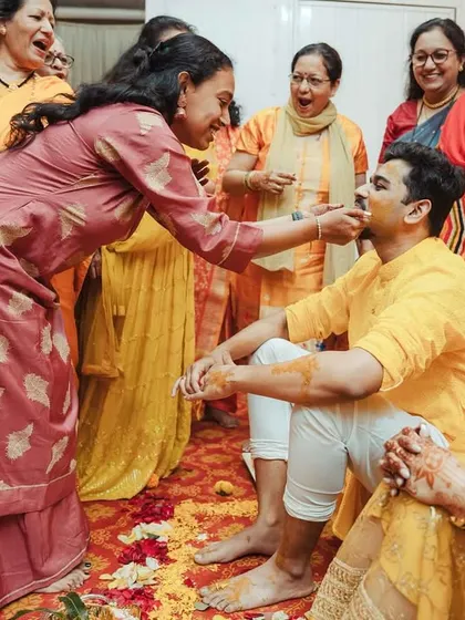 A family member applies Haldi to the groom, a moment of tradition and blessing.
