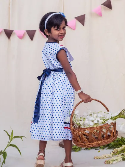 A charming back view of the sailor-style polka dot dress, showing the navy sash that ties into a lovely bow. It's a sweet detail that adds to its classic appeal.