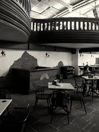 A view of the seating area, showing the contrast between the rough, exposed brick walls and the finished wooden furniture and balcony.