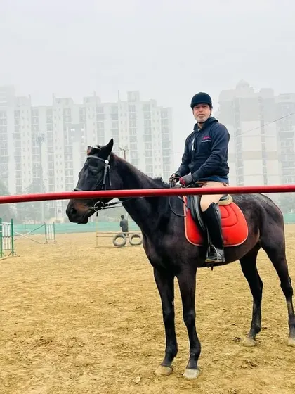 A rider takes a break during a lesson, posing on his horse inside the arena.