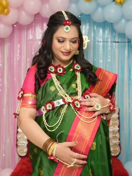 A lovely baby shower look featuring a traditional green saree and beautiful floral jewelry. The makeup is kept soft and pretty to match the occasion.