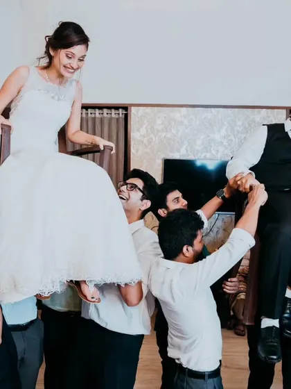 The bride and groom holding hands while being lifted on chairs, a symbol of their connection even amidst the fun chaos.