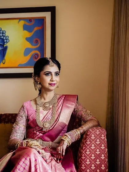 An elegant bridal portrait, with the bride seated gracefully on a couch. The artwork on the wall and the soft window light add to the sophisticated and artistic feel of the photograph.