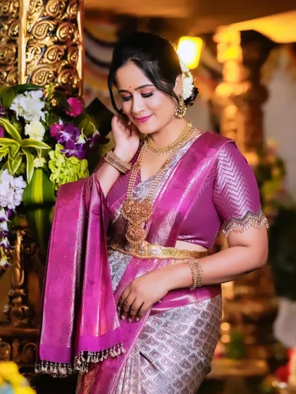 A beautiful candid moment with Hemalatha, as she adjusts her hair, showcasing the stunning temple jewelry paired with the saree.