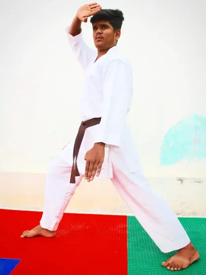 A student demonstrates a perfect blocking technique in a deep zenkutsu-dachi stance. Proper form is the essence of true martial arts, and we insist on its mastery.