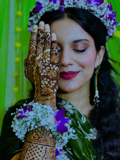 A serene shot of the bride, with her eyes closed, showcasing the intricate henna on her hand.