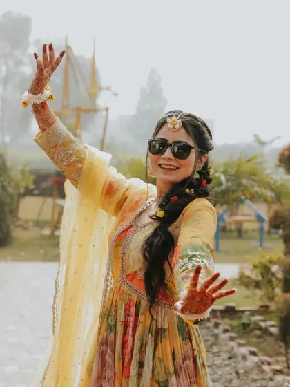 The bride's joyful dance at her Haldi ceremony. Her sunglasses and carefree attitude make for a fun and memorable photo.