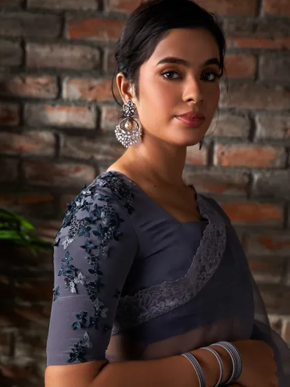 Embrace grace in every step. A close-up of the custom blouse paired with a grey organza saree, featuring delicate floral embroidery on the sleeves and back.