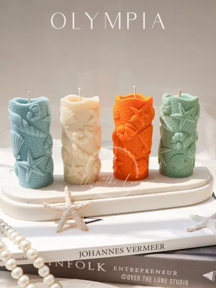 These new pillar candles from the Olympia collection feature a beautiful sea-themed design with starfish and shells. They bring a touch of the ocean to the classical aesthetic.