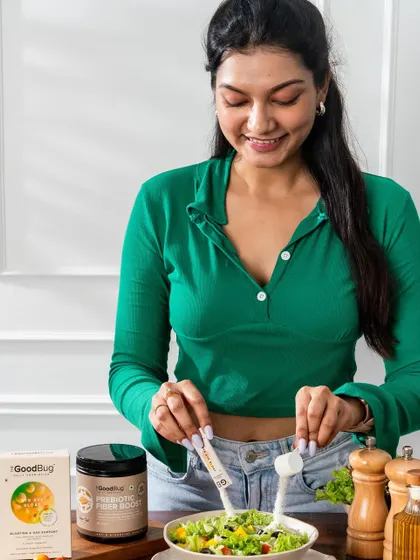 A lifestyle shot of a model adding a health supplement to her salad, demonstrating a healthy and easy use case.