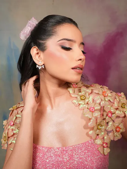 A soft girl glam look with a unique floral shoulder piece. The makeup is kept soft and pretty to complement the whimsical styling.