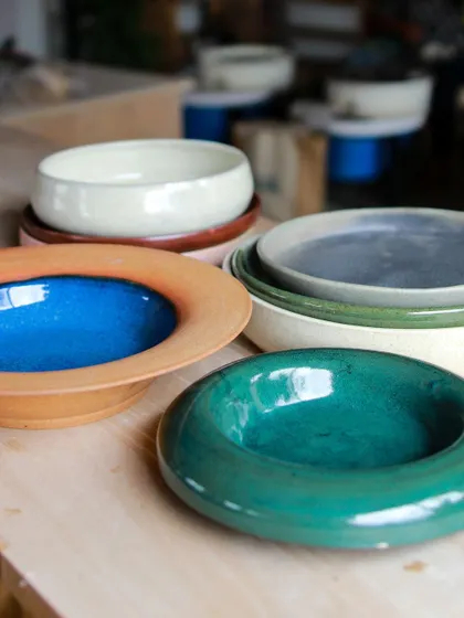 A collection of colorful, wide-rimmed bowls made by my students. Their journey from struggling to center clay to creating these confident forms is inspiring.