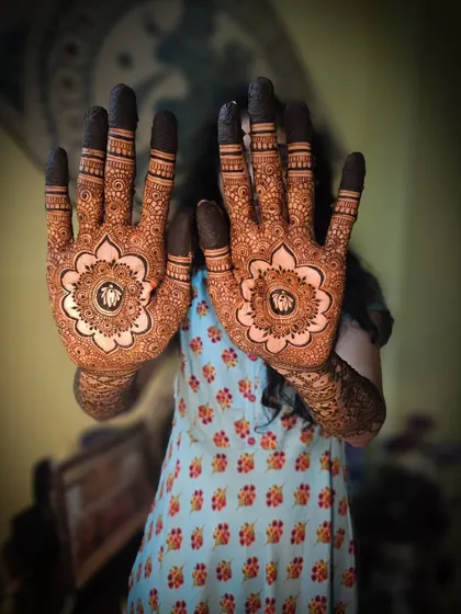 A classic bridal pose showing off matching mandala designs with personalized initials in the center. This is a popular choice for modern brides.