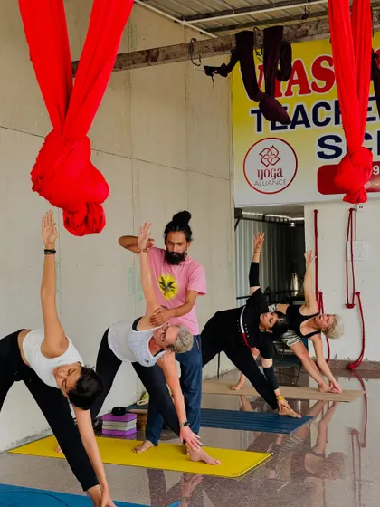 In Trikonasana, or Triangle Pose, proper alignment is crucial. I am adjusting a student to ensure her spine is long and her chest is open, demonstrating the finer points of the asana.