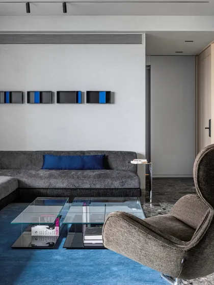 A detail shot of the seating area, featuring a classic high-back armchair against a wall with cementitious lime plaster.