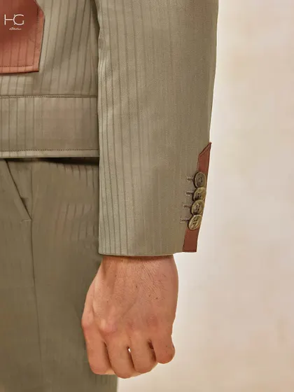 A close-up of the sleeve of a striped suit, showing the contrast cuff and button details. This is an ensemble designed to capture attention with its refined, fashion-forward elements.