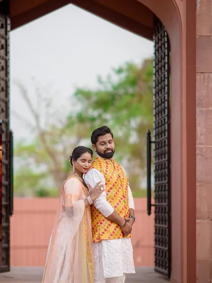 A tender moment captured at the entrance of a beautiful location. The bride-to-be rests her head on her partner's shoulder, conveying a sense of comfort and love.