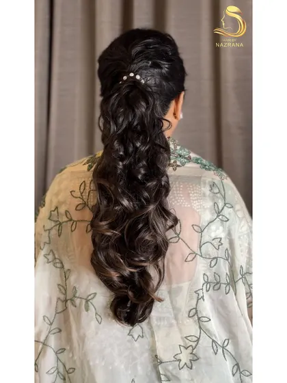 The back view of this textured ponytail shows the beautiful interplay of curls and volume, with a few pearl details for a touch of sophistication.