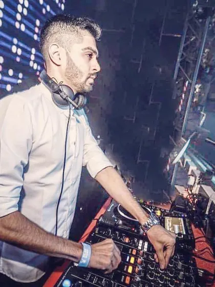 A clean, professional shot of me working the decks in a white shirt, with a large LED screen in the background. This demonstrates my experience playing in modern clubs with advanced visual setups.