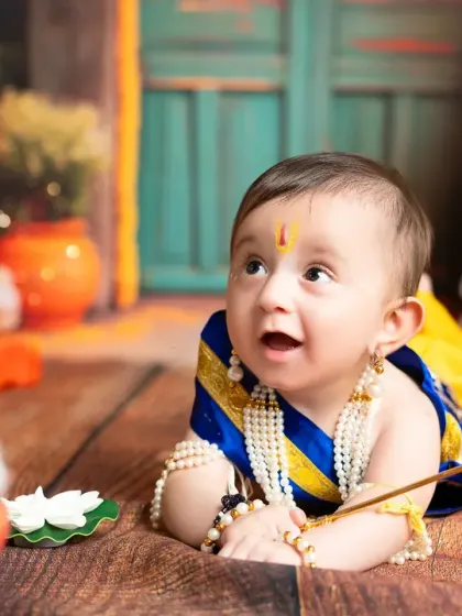 An expressive, low-angle shot of a baby boy in his Krishna costume, looking up with wonder. I work at the child's pace to capture their natural expressions.