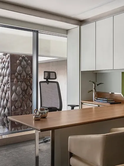 This cabin in 'The Layered Office' is designed for simplicity and functionality, with a large desk and integrated storage. A full-height window provides a direct view into the central courtyard, connecting the workspace with the building's core architectural feature.