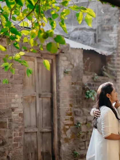 A beautiful moment framed by green leaves. The sunlight filtering through the trees creates a soft, natural, and romantic light.