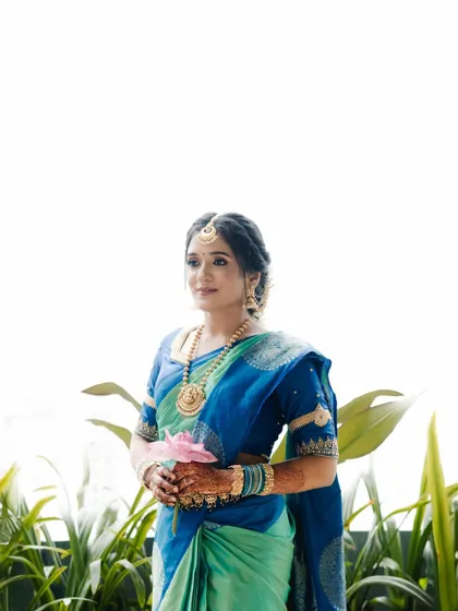 The bride holding a single pink lotus, a symbol of purity and beauty. This simple, elegant portrait is both traditional and modern in its composition.