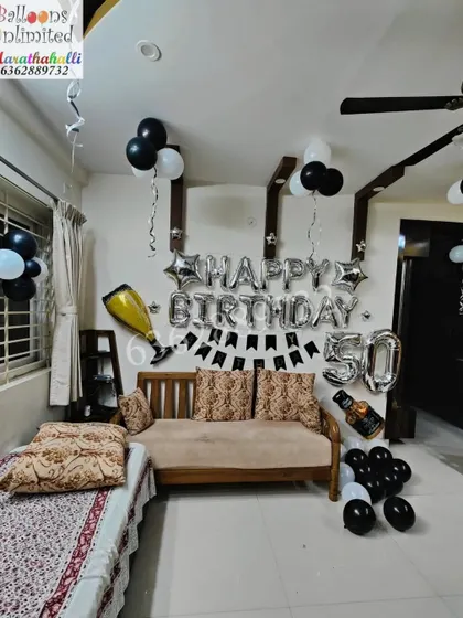 Another look at the 50th birthday home decoration, showing the 'Happy Birthday' foil balloons and champagne bottle prop.