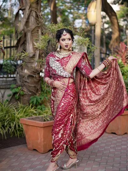 A full-length view of a bride in a stunning maroon `Navari` saree. I ensure the draping is perfect to create an elegant and powerful silhouette for the modern Maharashtrian bride.