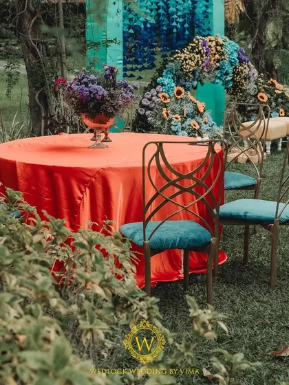 A vibrant floral backdrop and welcome sign for a colorful Haldi and Mehendi ceremony. The mix of orange, blue, purple, and yellow flowers created a stunning photo opportunity for the couple and their guests.