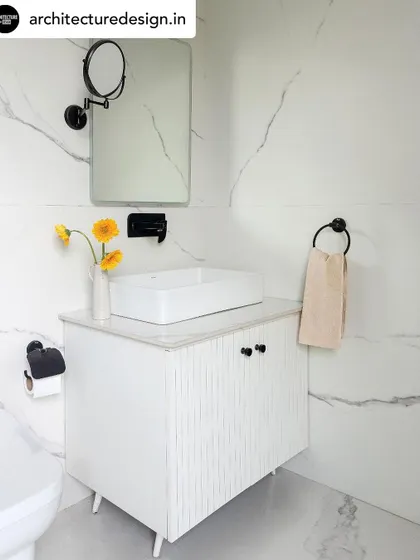 In contrast, this bathroom is bright and serene. White marble-patterned tiles are paired with a minimalist white vanity and matte black fixtures for a clean, contemporary look.