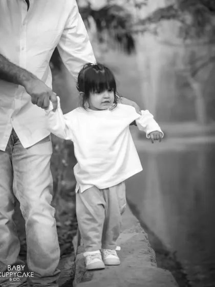 A father carefully guides his daughter as she walks along a ledge. A beautiful moment of trust and support.