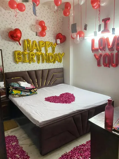 Here is another angle of a personalized birthday and romance combo setup. You can see the heart made of rose petals on the bed and the pathway on the floor, alongside 'Happy Birthday' and 'I Love You' foil balloons.