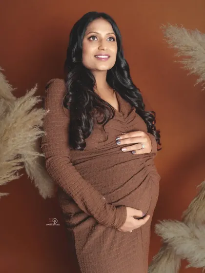 Embracing earthy tones and bohemian vibes in the studio. This mom-to-be looks radiant in a comfortable brown wrap dress, framed by pampas grass for a natural, warm feel.