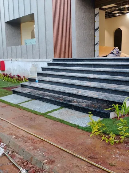 Integrating greenery with architecture, this design uses small lawn patches and planters to soften the look of modern black marble steps.