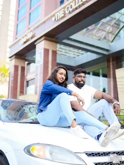 A cool, stylish shot of the couple sitting on the hood of a car in front of a modern building. This has a very cinematic, city-life feel.