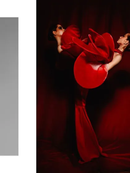 A dramatic, artistic composition featuring two models intertwined in a flowing red gown. The styling focuses on creating a single, fluid shape, exploring themes of connection and movement through a bold, monochromatic palette.