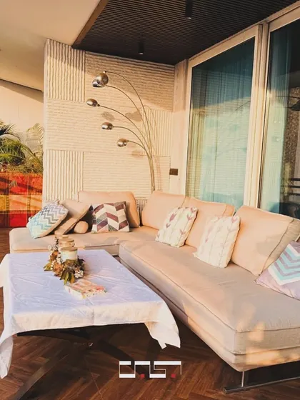 This cozy corner of the balcony features a plush sectional sofa with plenty of cushions, making it the perfect spot for an afternoon nap or reading a book outdoors.