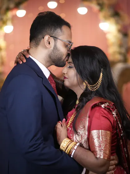A tender forehead kiss, a moment of pure affection. This intimate portrait from a Bengali wedding reception highlights the couple's deep bond.