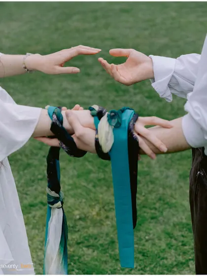 A close-up of the hand-fasting ritual, where colorful ribbons bind the couple's hands together, symbolizing their unbreakable bond and shared future.